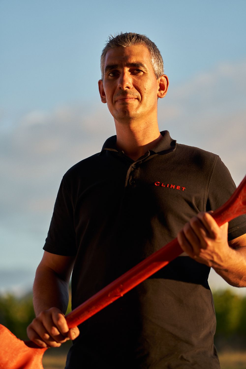 Portrait of a vineyard worker holding a shovel, sunset light on his face.