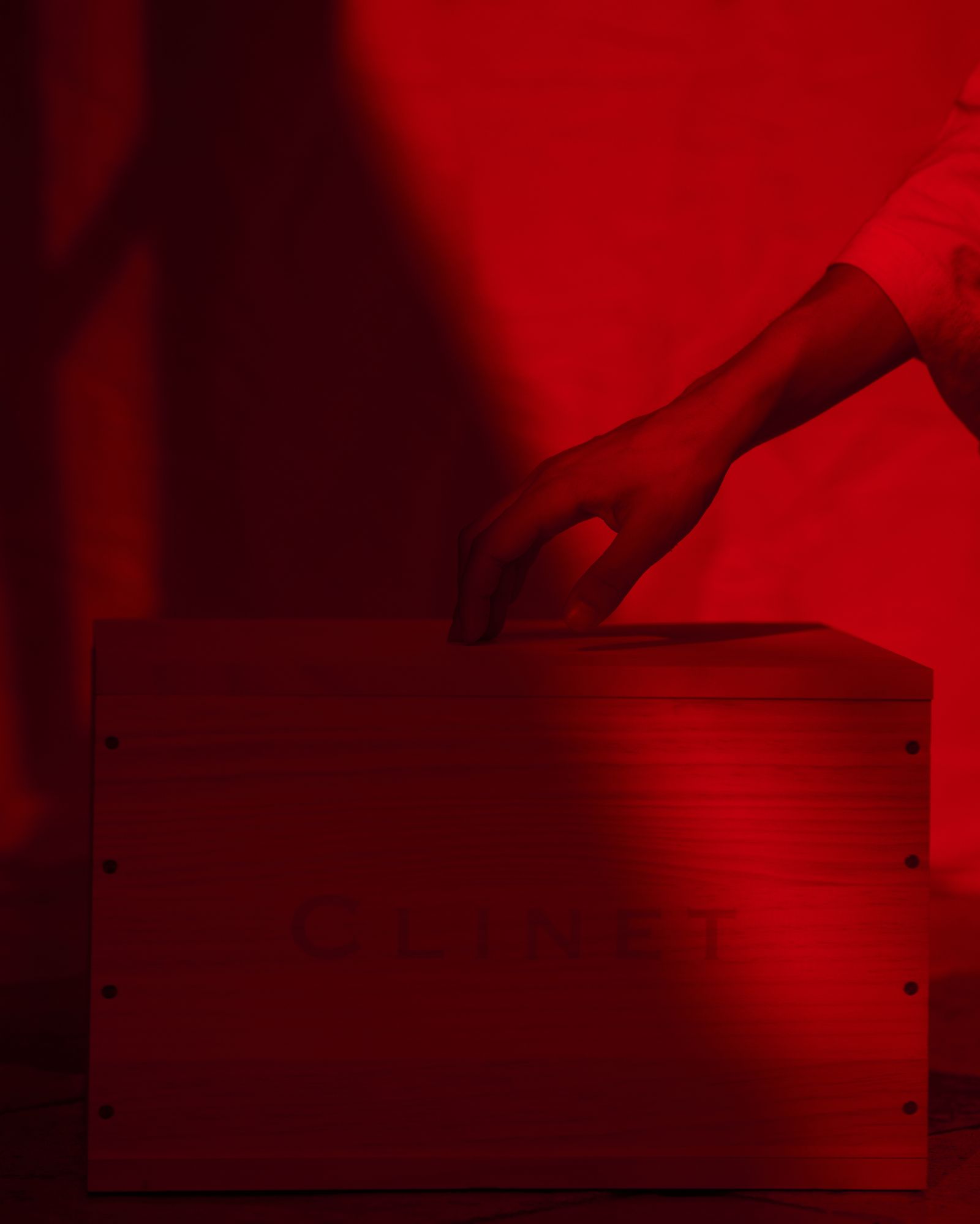 Red filter photo showing girl's hand touching top of wooden crate of Clinet wine