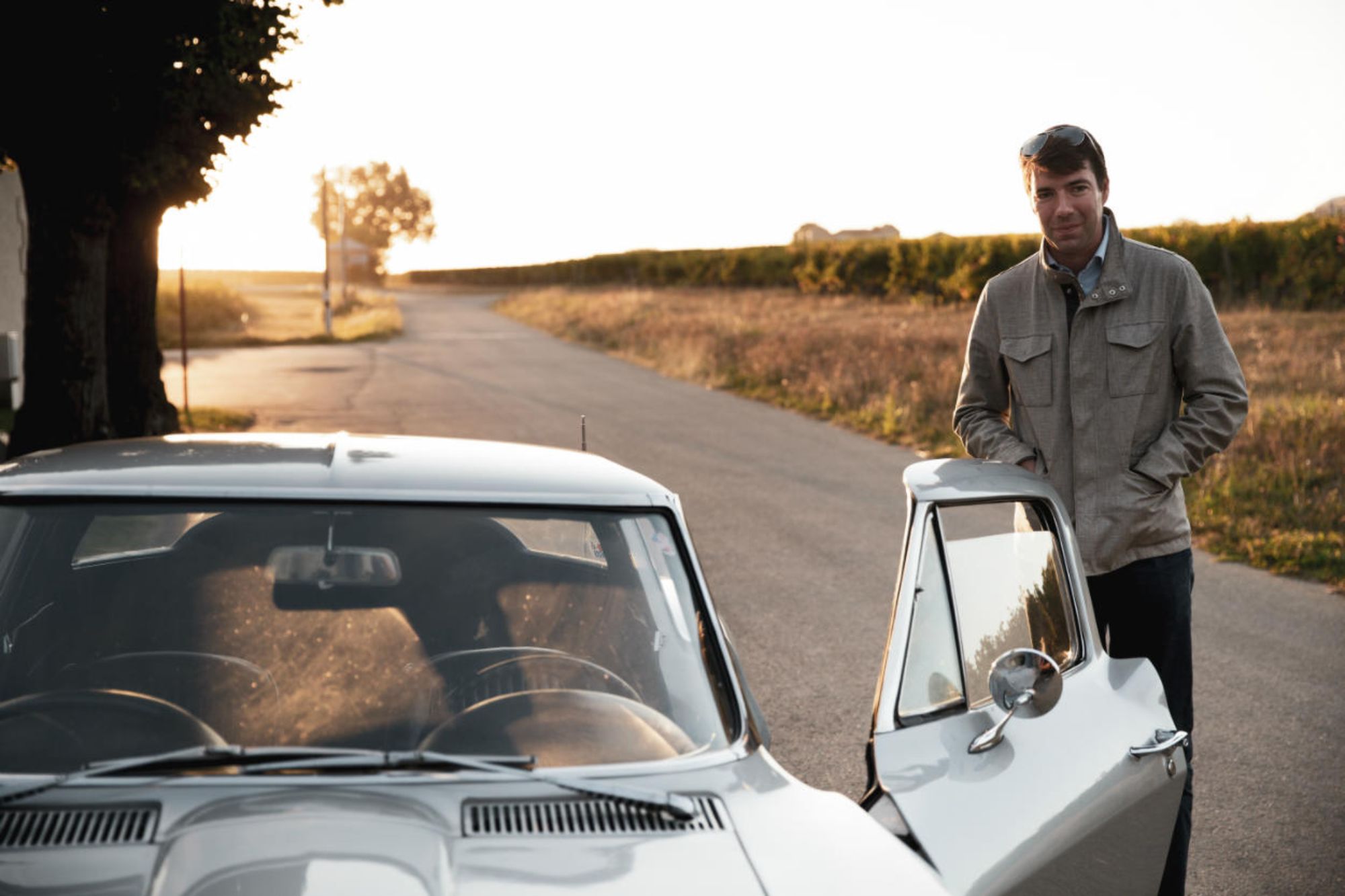 Ronan Laborde stands beside his car on a country lane between the vines.